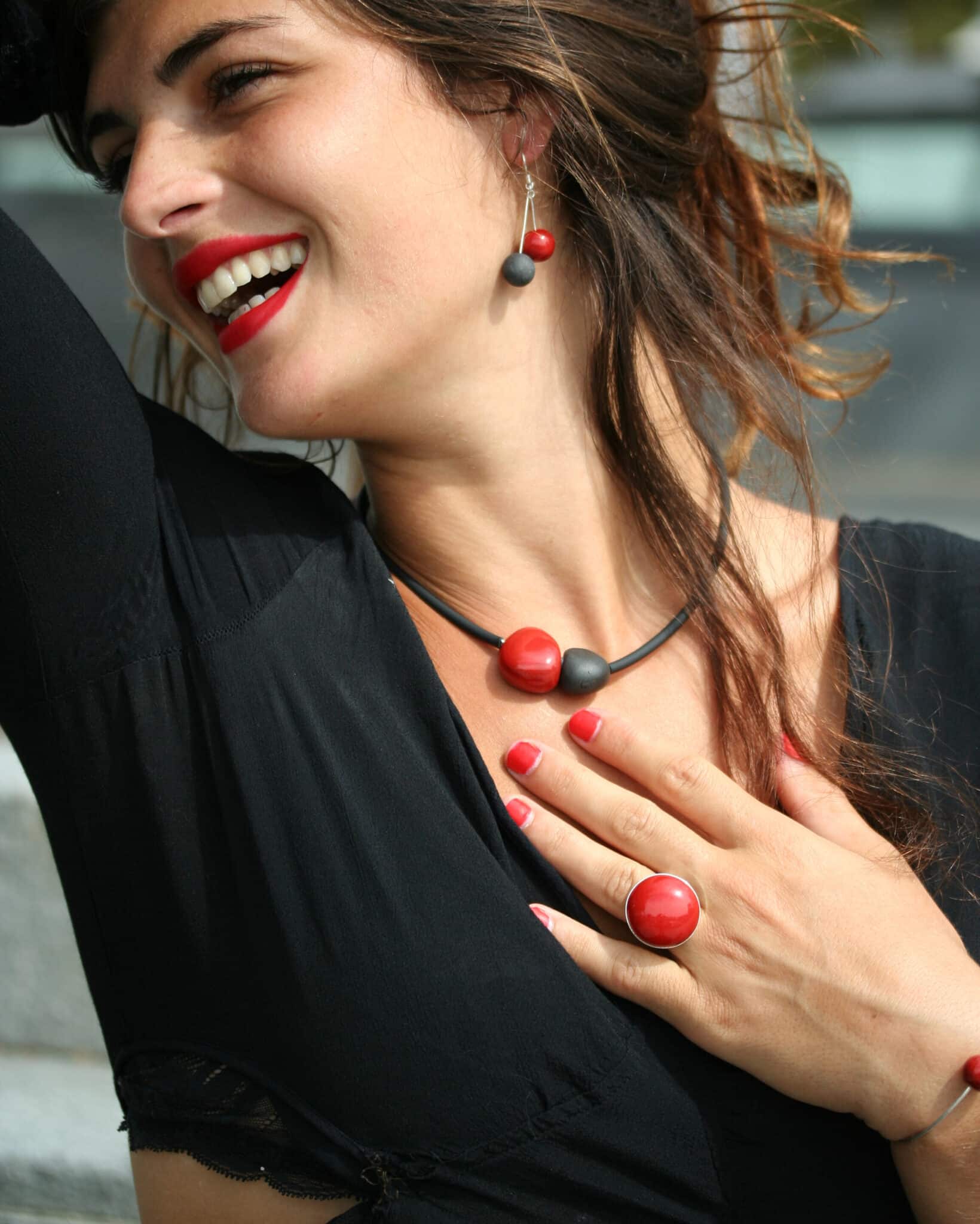 Bijou artisanal en céramique couleur cerise sur une main