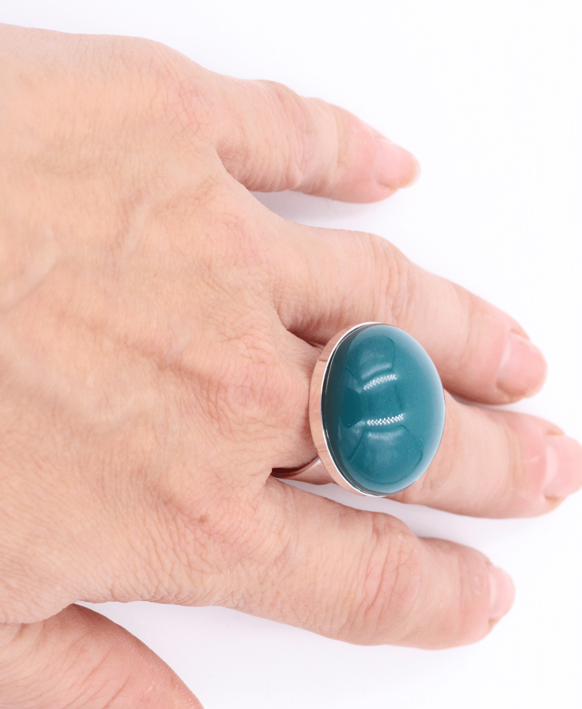 Bijou artisanal en céramique couleur bleu canard sur une main